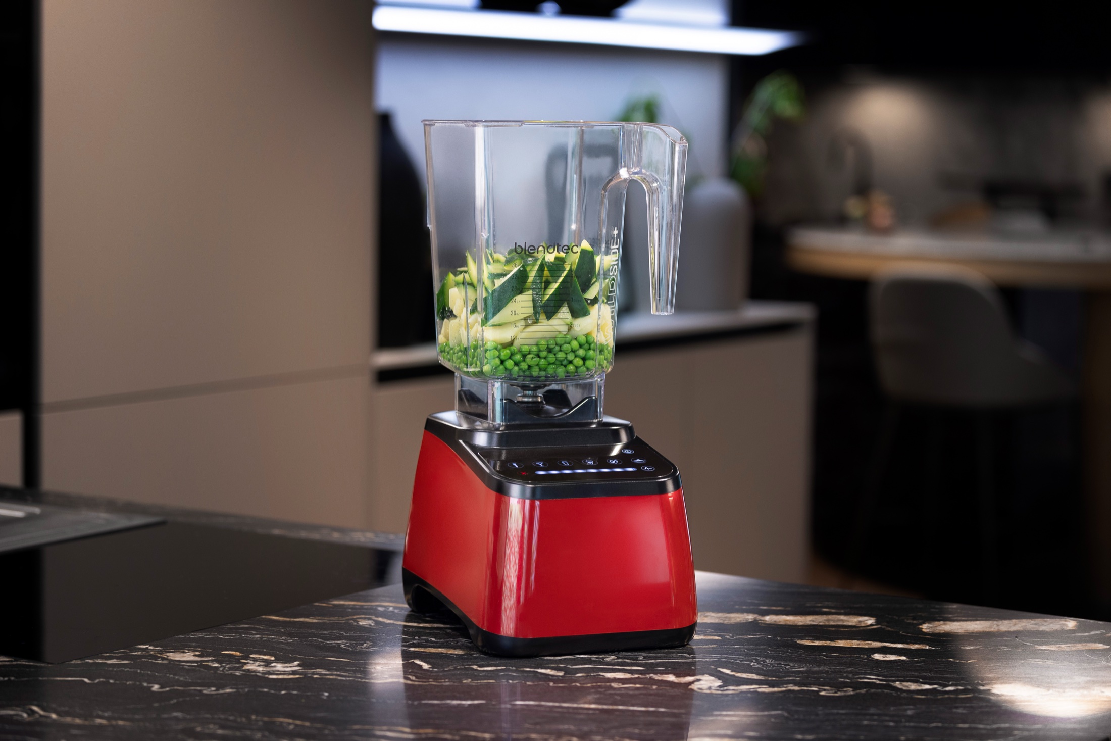 Frullatore Blendtec rosso con verdure nel bicchiere, su un piano in pietra